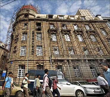 Commuters walk past the headquarters of Central Bank of India in Mumbai.