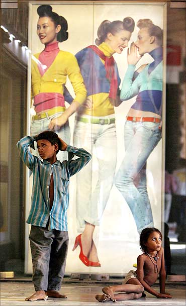 Homeless children are seen in front of a display window of a garment showroom in New Delhi.