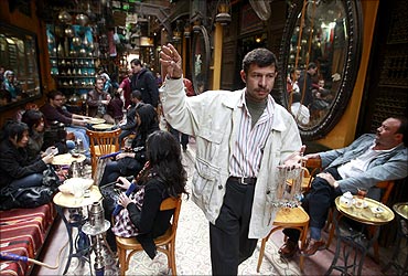 A street vendor selling necklaces passes through a famous shisha bar in the Khan al-Khalili area of Cairo.