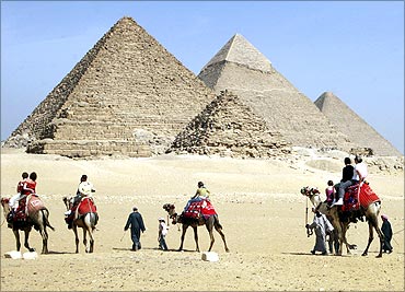 Tourists ride camels at the Pyramids in Cairo.