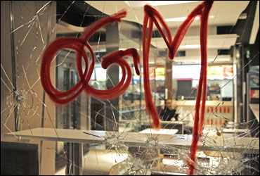 A tag OGM referring to genetically modified plants is seen sprayed on a broken window of a McDonald.