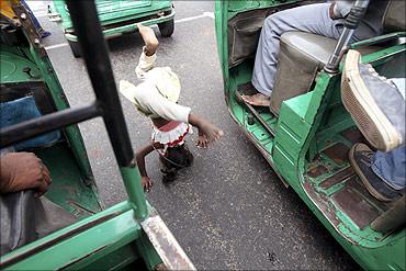 A girl street performer does a headstand at a traffic signal in New Delhi.