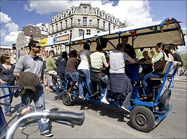 Tourists cycle as they drink beer and sing karaoke on a beer bike in Amsterdam.