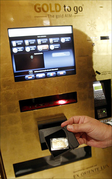 A man holds a gold bar after the unveiling of the first gold-plated ATM at a Madrid's luxury hotel.