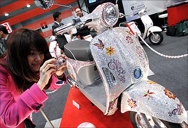 A woman takes a picture of Kymco scooter Mitch, studded with 100,000 Swarovski crystals.