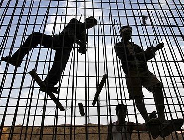 Labourers fasten iron rods together at the construction site of a commercial complex.