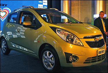 Karl Slym, president and managing director of General Motors India sits next to a Chevrolet Beat.