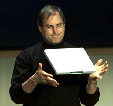Jobs throws the lightweight Apple iBook notebook computer up in the air on May 1, 2001.