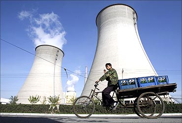 A worker drives his tricycle in front of a power plant on the outskirts of Beijing.