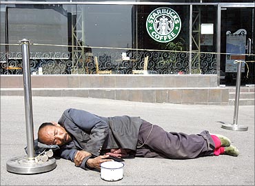 A beggar sleeps in front of a coffee shop in Beijing.