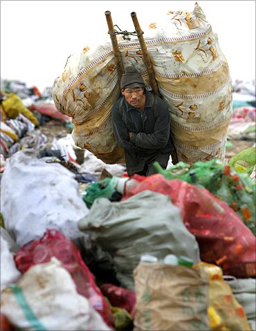 A man carries a package on his back at a garbage dump site in Nanjing.