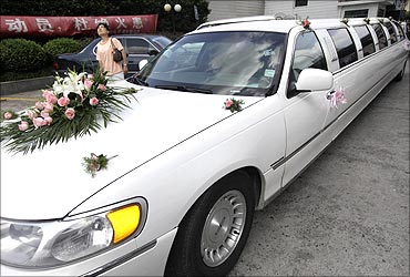 A woman looks on near a Lincoln limousine ferrying a couple for their wedding in Shanghai.