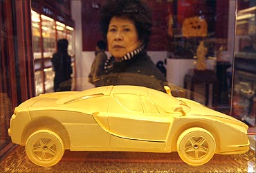 A woman looks at a gold car on display at China International Jewellery Fair in Beijing.