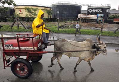 A worker transporting fuel in a bullock cart travels past Indian Oil Corporation's depot in Mumbai.