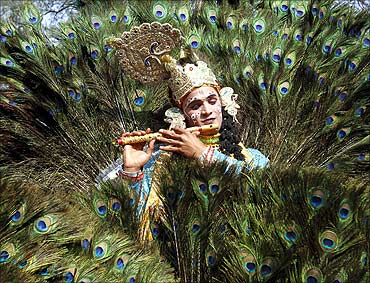 An artist dressed as Lord Krishna performs during a media preview of the 25th Surajkund Crafts Fair.