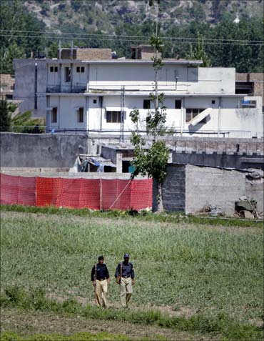Pakistani policemen walk past a compound where Osama was killed.