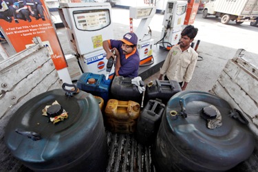 A worker fills plastic containers with diesel at a fuel station.