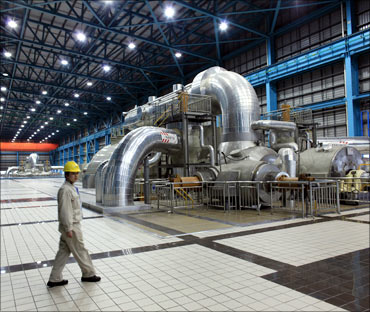 A power station staff worker walks past a steam-turbine power generator in the Waigaoqiao.