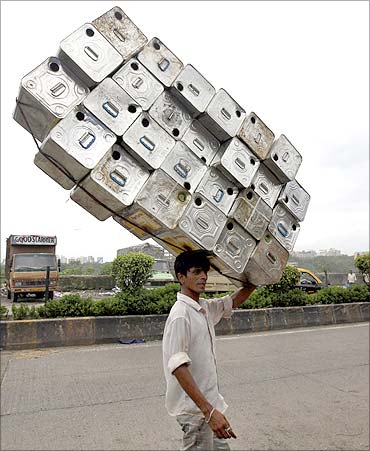 A labourer carries empty tins to a recycling factory in Mumbai.