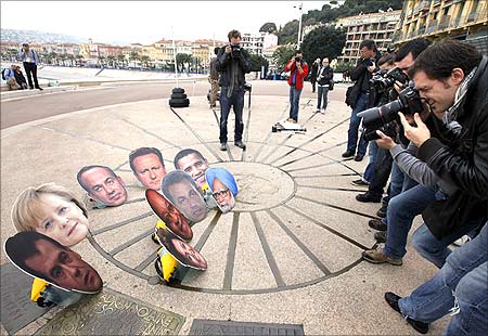 Photographers take photo of masks showing G20 leaders during an anti G20 demonstration.