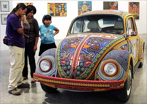 People look at a 1990s Volkswagen Beetle named Vochol during an exhibition on Huichol culture at the Museum of Puebla.