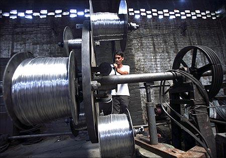 A worker winds aluminium and iron wires used to making electrical power lines at a factory on the outskirts of Jammu.