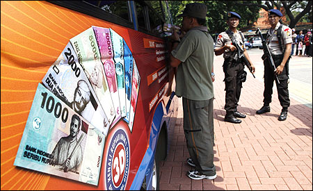 A man collects small rupiah banknotes from a mobile bank van in Jakarta.