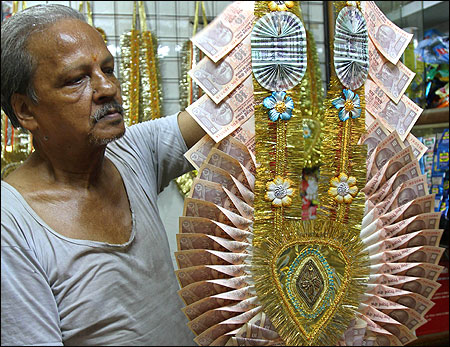 Dhanender Kumar Jain, 65, a shopkeeper, holds a garland made of rupee notes.