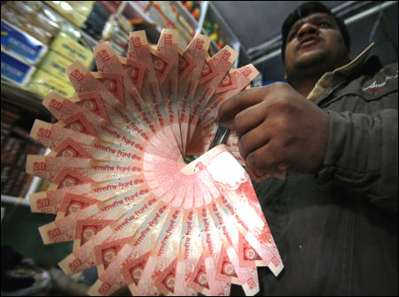 A shopkeeper holds a garland made of Rs 20 notes.