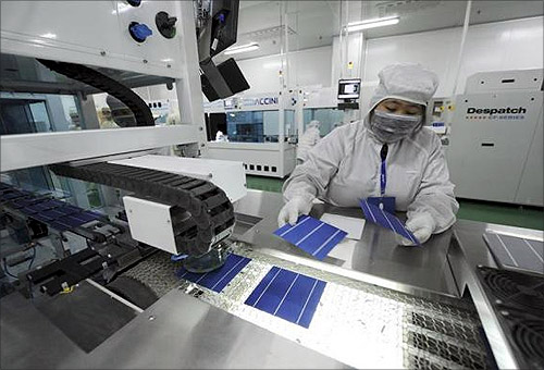 An employee inspects solar panels along a production line at an LDK Solar company workshop in Hefei, Anhui province.