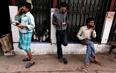People speak on wireless phones outside the PCO at a wholesale grocery market in Kolkata.