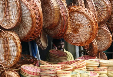 A basket maker speaks on a mobile phone as he waits for customers at a bamboo and cane baskets shop in Hyderabad.