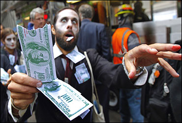 A demonstrator holds play money while dressed as a corporate zombie as he walks with others taking part in an Occupy Wall Street protest in lower Manhattan.