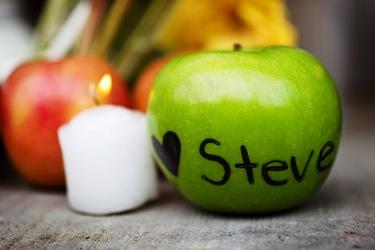 An apple with a heart and Steve Jobs' name written on it is placed in front of a small memorial in San Francisco.