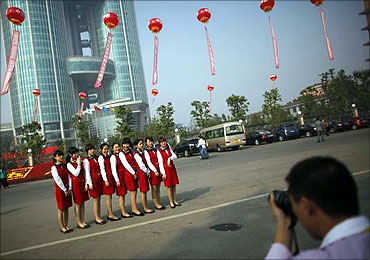 Women pose for a picture in front of the new skyscraper tower of Huaxi village.