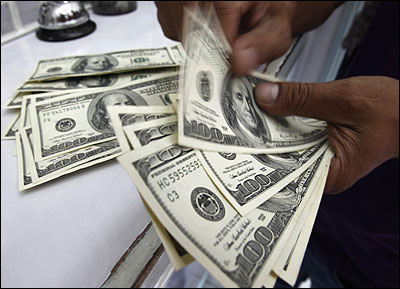 A worker counts US dollar bills at a money changer.