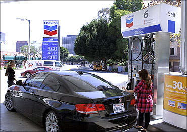 A woman stands at a petrol pump at a Chevron gasoline station in Los Angeles.