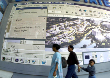 isitors pass a billboard showing a large computer screen at a stall during a fortnight-long international trade fair in New Delhi.