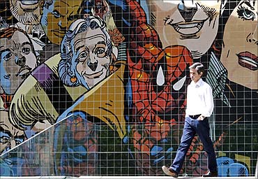 A man walks past a wall decorated with with comics characters on a street in Lisbon.