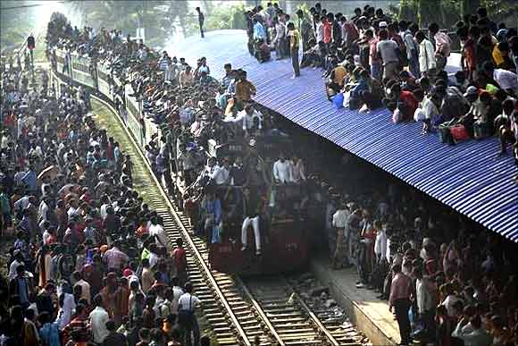 An overcrowded train approaches as other passengers wait to board at a railway station in Dhaka.