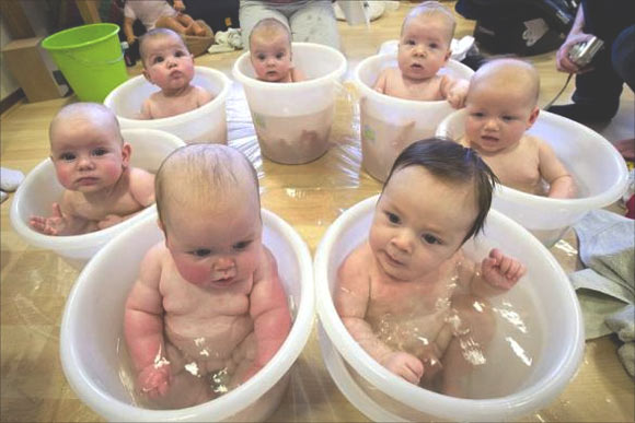 Babies sit in tummy tubs filled with water to cool down after a baby massage class held for young mothers in Netherlands.