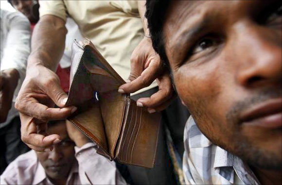 A migrant worker from Bangladesh shows his empty wallet to the camera as workers gather near a government office in Singapore.