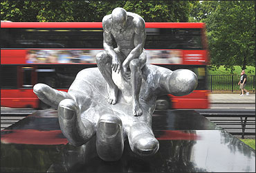 A double-decker bus passes the Hand of God sculpture in central London.