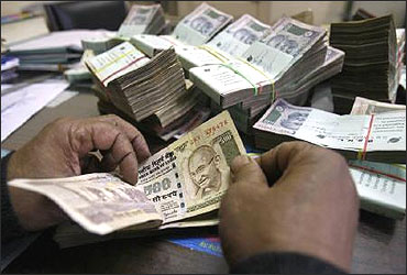 An employee counts rupee notes at a cash counter inside a bank in Agartala.
