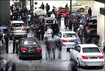 Visitors look at cars at the exhibitiuon booth of German luxury carmaker BMW.