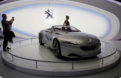 A visitor takes a picture of the Peugeot SR1 Concept car during the Moscow Auto Salon 2010.