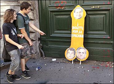 A couple walks past a banner during a demonstration in Rome.