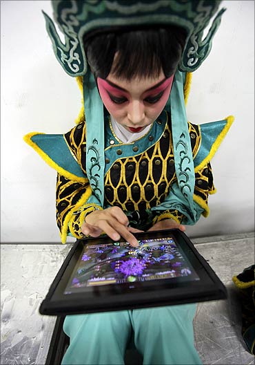 A performer plays a game on an iPad while waiting for a Beijing opera.