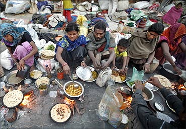 Homeless people prepare food on a roadside during the early morning in Ahmedabad.