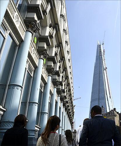 Pedestrians walk near the Shard building in central London.